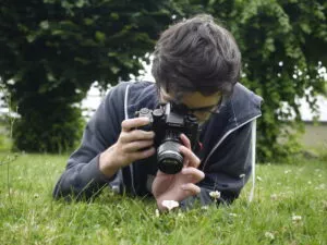 Lohan allongé dans l'herbe en train de photographier un insecte en macro